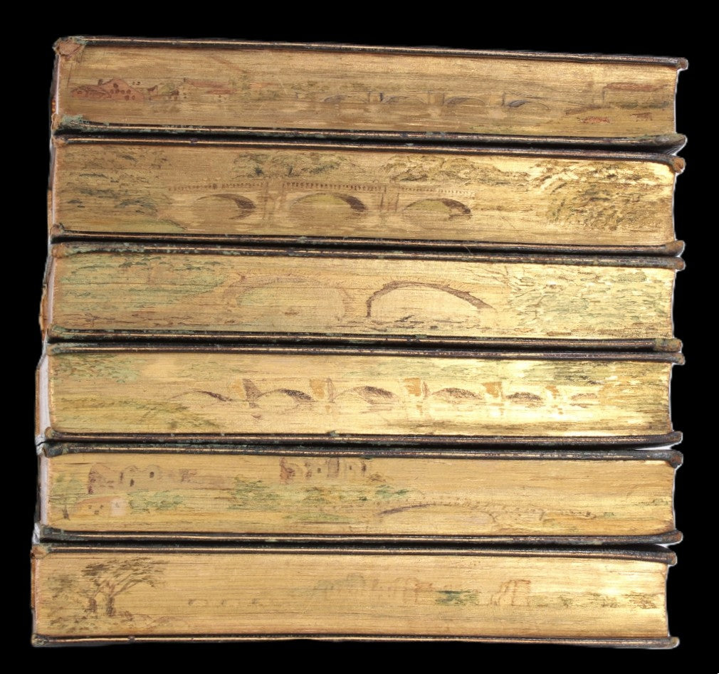 Stack of antique books with landscape fore-edge paintings of old European bridges.